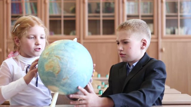 Children at elementary school. Children in geography lesson at school. Pupils view the globe in an elementary school class.