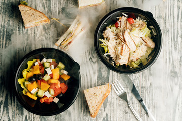 delicious Greek salad and Caesar salad with sandwiches on a grey wooden table