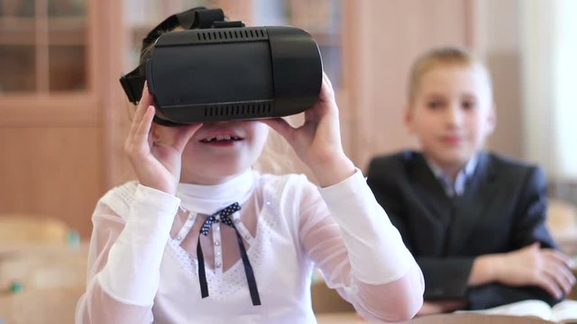 Virtual reality technology for children in a modern school. Schoolgirl use of VR goggles in lessons. Pupils online elementary school.