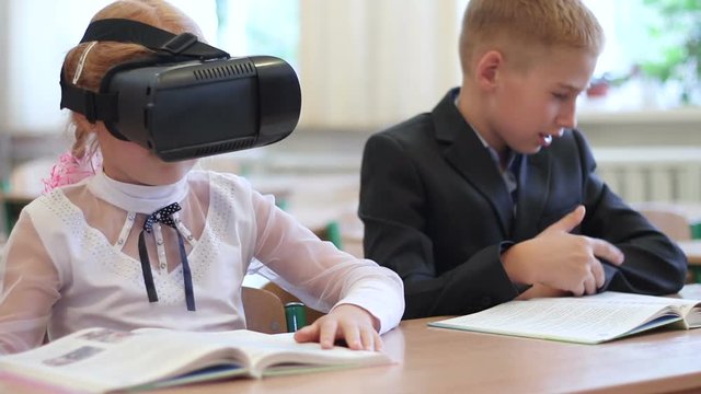 Schoolgirl use of VR goggles in lessons. Virtual reality technology for children in a modern school.