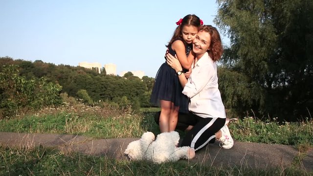 Happy mother and daughter outdoors. Family on a walk in summer forest with dog.