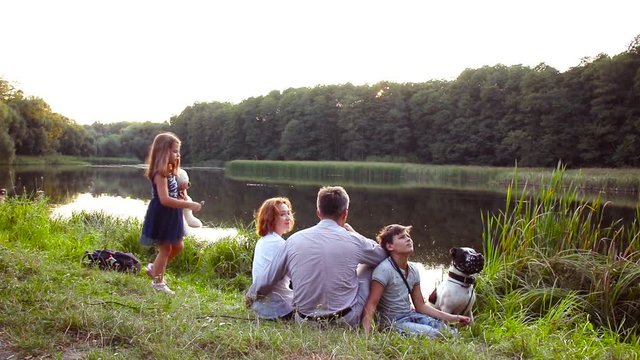 Mother, father and their children and dog walking in summer forest. Family outdoor leisure in park. Happy family's on vacation by the lake.