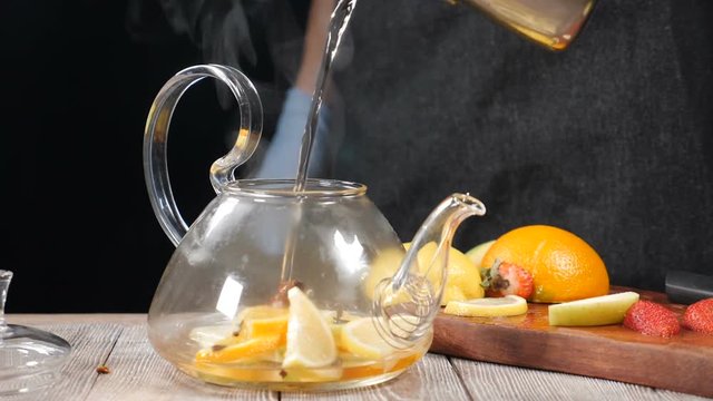 Closeup shot of boiled water being poured into teapot wuth fruit. Tea brewing concept. Slow motion. Pouring water in glass tea kettle , brewing Chinese tea. hd