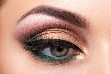 Obraz premium Close up of beautiful woman eye with multicolored smokey eyes makeup. Modern fashion make up. Studio shot