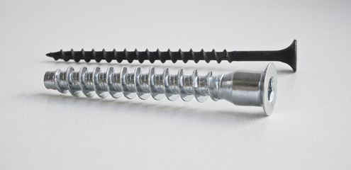 Isolated object - shiny and new furniture screw-bolt and black screw on wood on a light background