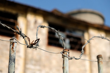 Rusty barbed wire on a fence of a deserted industrial ruin