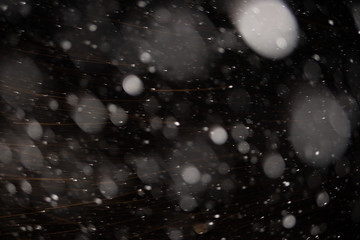Background of falling snowflakes in the light of a lantern.