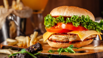 American cuisine concept. Juicy burger with meat patty, tomatoes, cheddar cheese, lettuce and...