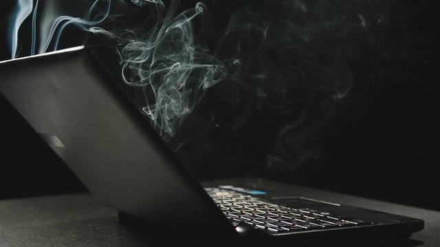 SIDE VIEW: Laptop is emitting smoke - Slow Motion