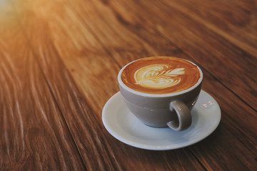 A latte coffee mug on the brown wood table with morning light