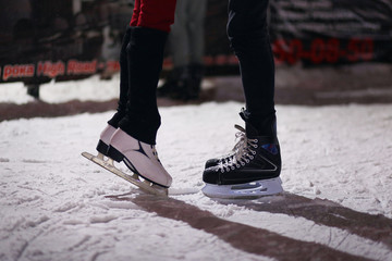 Legs of loving couple on skates. The guy and the girl are engaged in figure skating on an ice skating rink at night