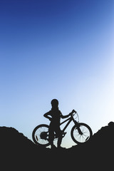 Obraz premium Silhouette of a little girl with a bicycle at sunset