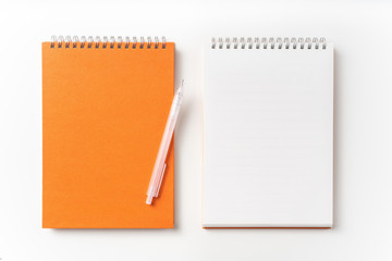 Top view of orange spiral notebook, page, pencil