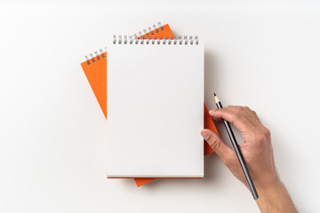 Top view of orange spiral notebook, page, pencil