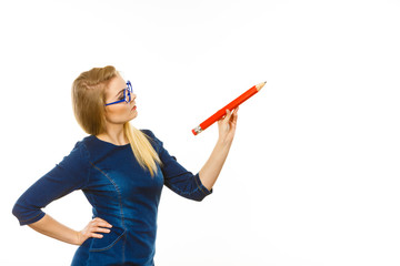 Serious woman holds big pencil in hand