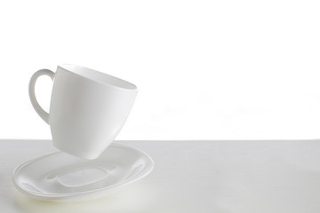 White cup with saucer in a jump on a white background. Jumping cup. Flying dishes on a white background.White dishes on a white background