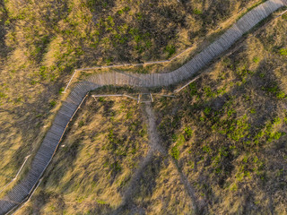 Drone bird's eye aerial view of grassy sand dunes on beach landscape at sunrise on English coast