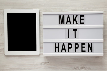 Lightbox with text 'Make it happen', tablet with blank screen on a white wooden background, top...