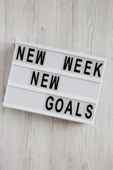 Modern board with text 'New week new goals' over white wooden background, top view. From above, flat lay, overhead.