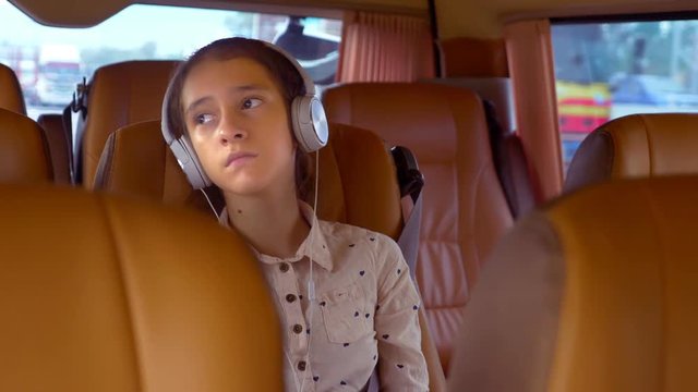 The concept of summer vacation, travel. teen girl rides in a minivan with headphones