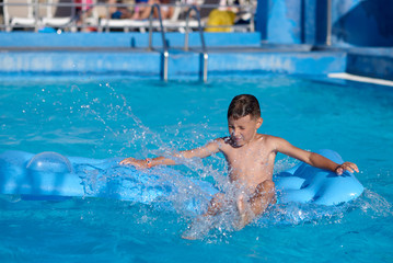 Cute European boy is diving from the inflatable blue floater into the hotel&rsquo;s swimming pool. He is enjoying his summer vacations.
