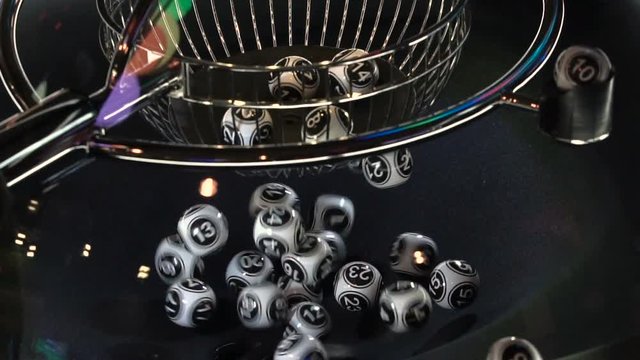 Black and white lottery balls in a rotating bingo machine. Slow motion.
