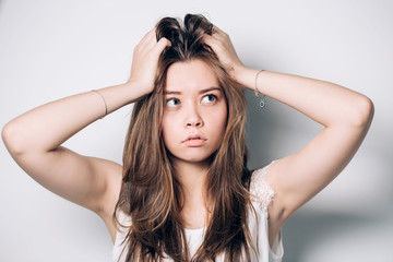 Fototapeta premium Closeup portrait of the beautiful young woman on the white background. Beautiful young girl looks up, thinks, dreams, doubts. Emotional face.