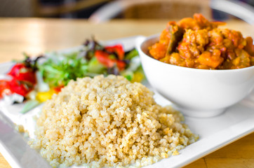 Vegan gluten free meal with white quinoa and a pumpkin curry served with salad