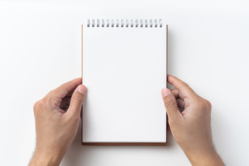 Top view of brown spiral notebook with hand