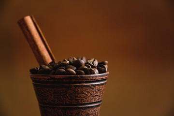 Clay cup with coffee beans and cinnamon on a wooden table
