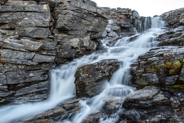 A waterfall in wild mountains in the Troms Region in Northern Norway above the Polar Circle