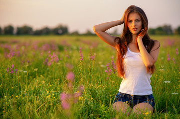 Naklejka na ściany i meble Beautiful girl is on nature on the spring wildflowers background.