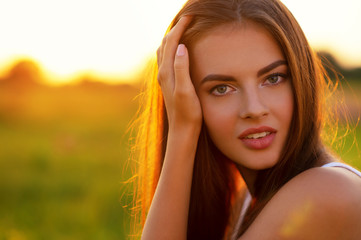 Beautiful young woman on nature over summer sunset.