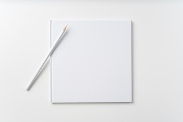 Top view of white notebook, page, pencil