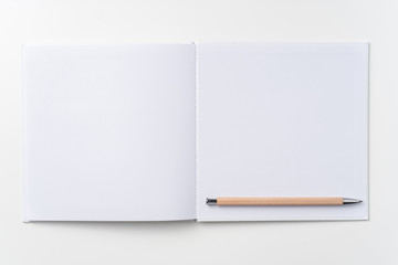 Top view of white notebook, page, pencil