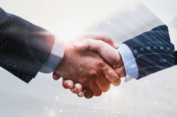 double exposure of business man handshake on modern office building background with network...