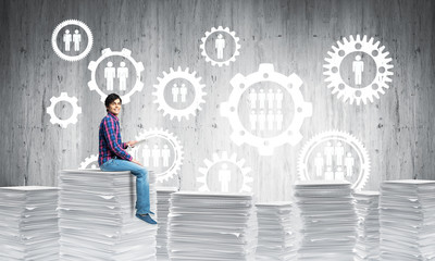 Attractive man sitting on pile of paper documents.
