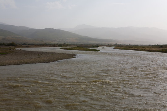 Rushing stream of the river and the mountains in the haze.