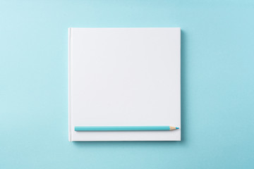 Top view of white hardcover notebook, pencil