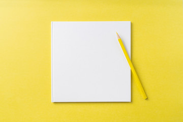 Top view of white hardcover notebook, pencil