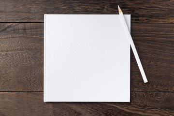 Top view of white hardcover notebook, pencil
