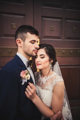Portrait of a stylish young couple at the wedding photo shoot, the girl hugs her husband's face