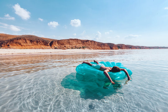 Man Relaxing On Inflatable Ring On The Beach