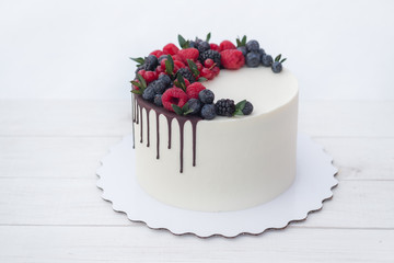 beautiful homemade birthday cake with white cream and natural berries on white background