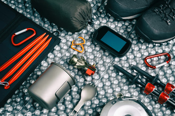 camping equipment top view includes trekking shoes, gas stove, titanium mug, navigator, tent poles,...