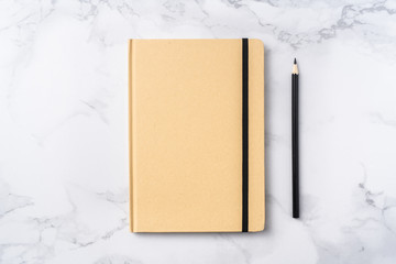 Top view of kraft paper notebook, pencil