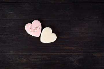 Sweets on Valentine's Day. Cookies in shape of heart and with lettering Love on dark wooden background top view copy space