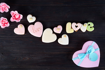 Sweets on Valentine's Day. Cookies in shape of heart and with lettering Love on dark wooden background top view copy space