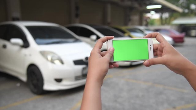 A women uses his smartphone to observe the ride sharing traffic patterns on an interactive map green screen.