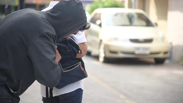 A woman on a city street does not suspect that her phone was stolen by a sly pickpocket. It crosses the road through a pedestrian crossing. The thief stole her cell phone from the bag